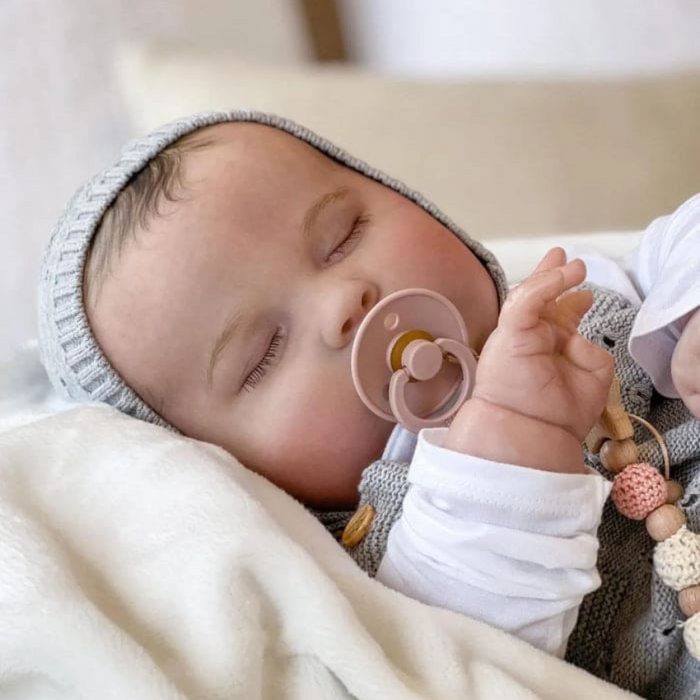 Bebê Reborn João Guilherme 60cm, boneco realista de silicone com olhos fechados, cabelo pintado e acessórios. Perfeito para crianças 3+, fomenta cuidado e imaginação!