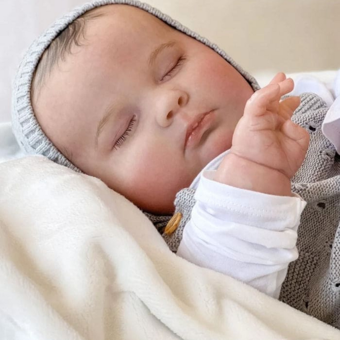 Bebê Reborn João Guilherme 60cm, boneco realista de silicone com olhos fechados, cabelo pintado e acessórios. Perfeito para crianças 3+, fomenta cuidado e imaginação!