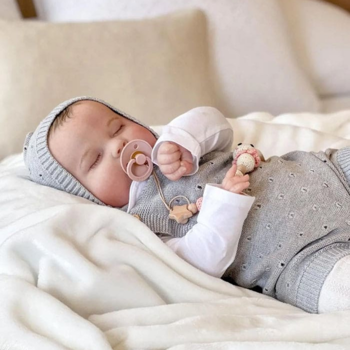 Bebê Reborn João Guilherme 60cm, boneco realista de silicone com olhos fechados, cabelo pintado e acessórios. Perfeito para crianças 3+, fomenta cuidado e imaginação!